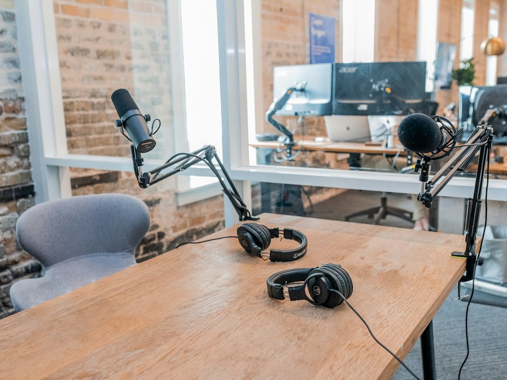 A room with a wood table. On the table are headphones and a recording microphone